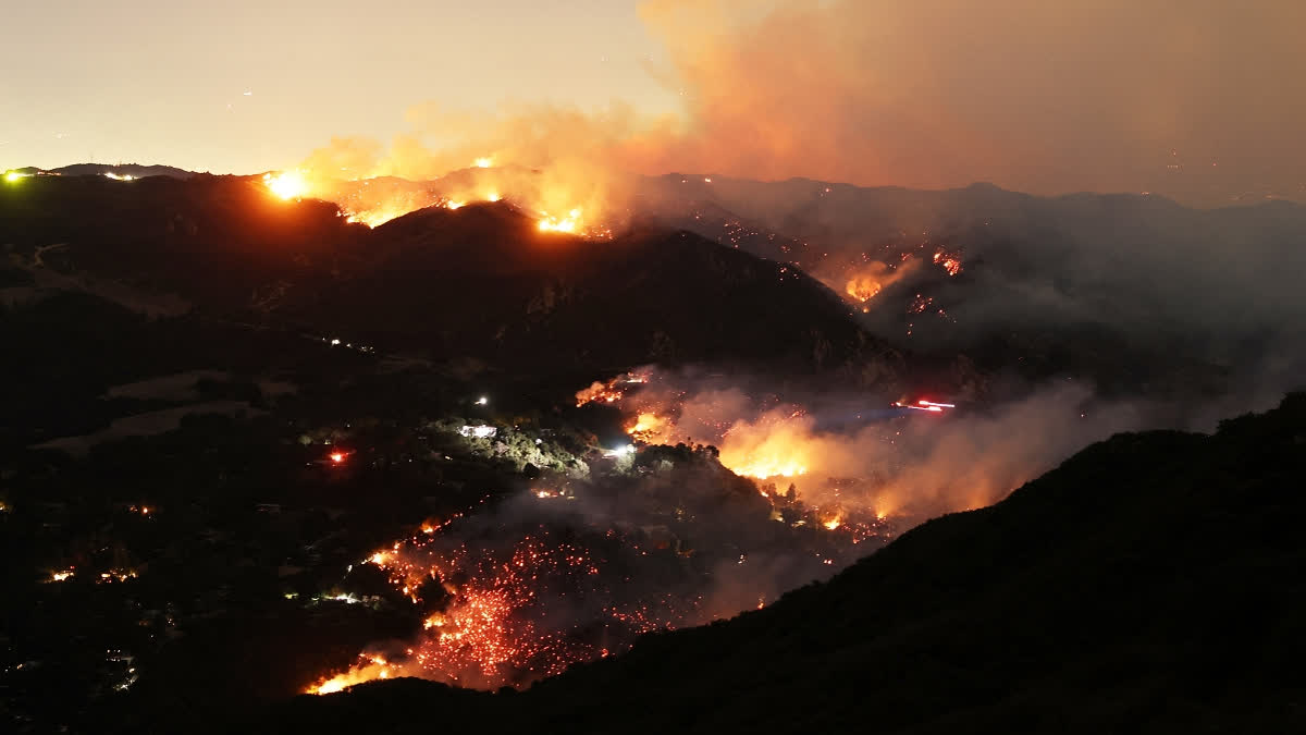 Flames and smoke from the Palisades Fire surround a home (C) in the community of Topanga, California, on January 9, 2025. The two largest fires burning in Los Angeles remain "zero percent" contained on January 9 despite firefighting operations, officials said, as they also vowed to tackle looting of evacuated homes.