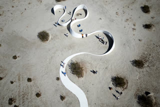 Aerial view of French-American artist Sarah Meyohas' piece "Truth Arrives in Slanted Beams," which uses curved metallic mirrors to reflect and refract sunlight, beaming the words across the sides of a meandering wall during the media preview day of the Desert X exhibit, in the Coachella Valley near Desert Hot Springs, California, on March 7, 2025.