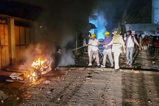 Police personnel try to douse a fire after clashes in Mhow on Sunday.
