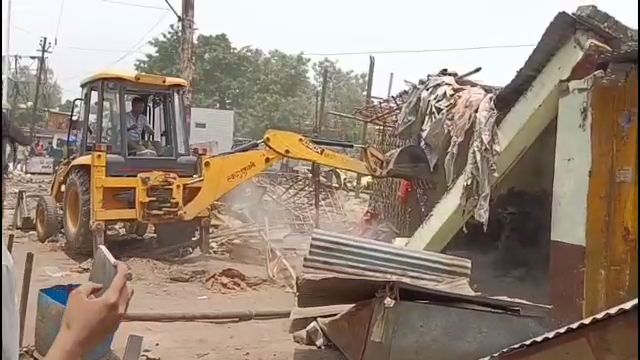 अवैध दुकानों को गिराता बुलडोजर.