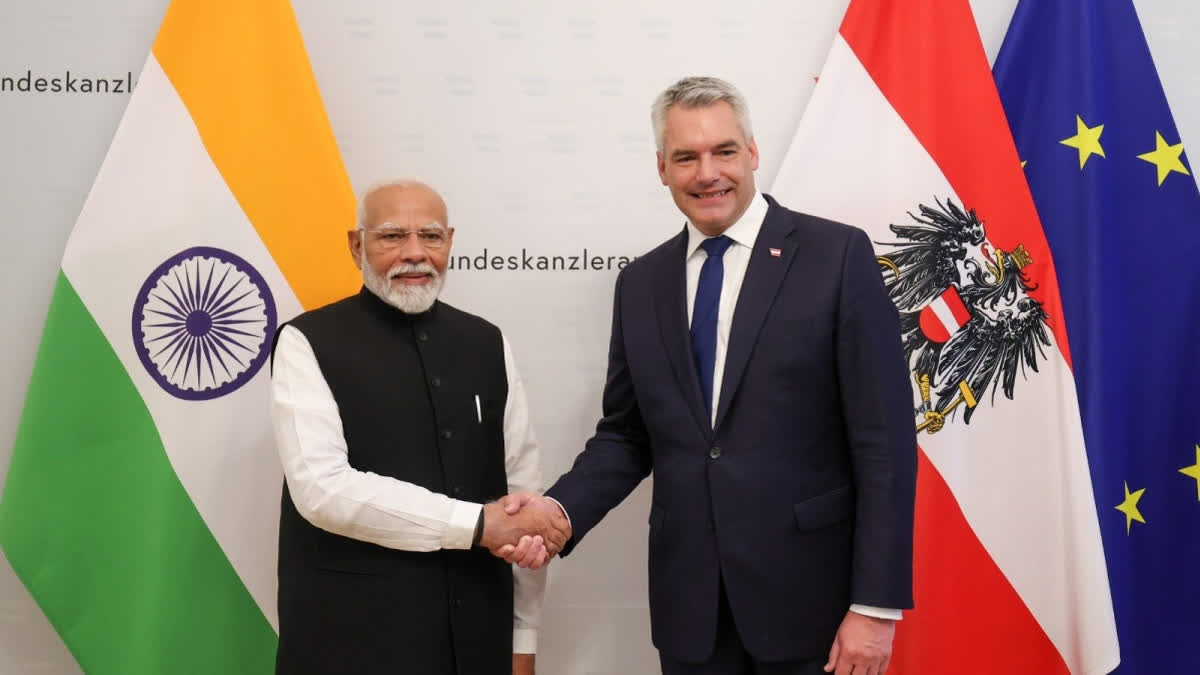 Prime Minister Narendra Modi exchanges greetings with Austrian Federal Chancellor Karl Nehammer after signing the Guestbook at the Federal Chancellery, in Vienna.