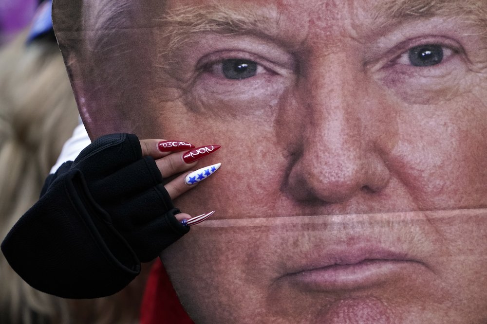 A woman holds a cut out of President Donald Trump's face Wednesday, Jan. 6, 2021, in Washington, at a rally in support of President Donald Trump called the 