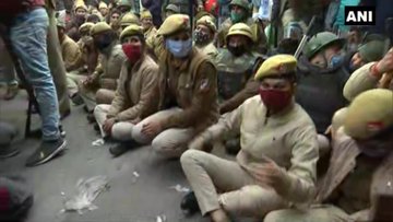 Police officials sit on road in Nangloi to block the area where farmers holding tractor parade have reached