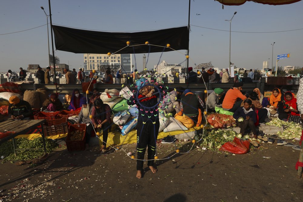 A protesting farmer child shows his skill as others prepare food as they camp on a highway at the Delhi- Uttar Pradesh border,