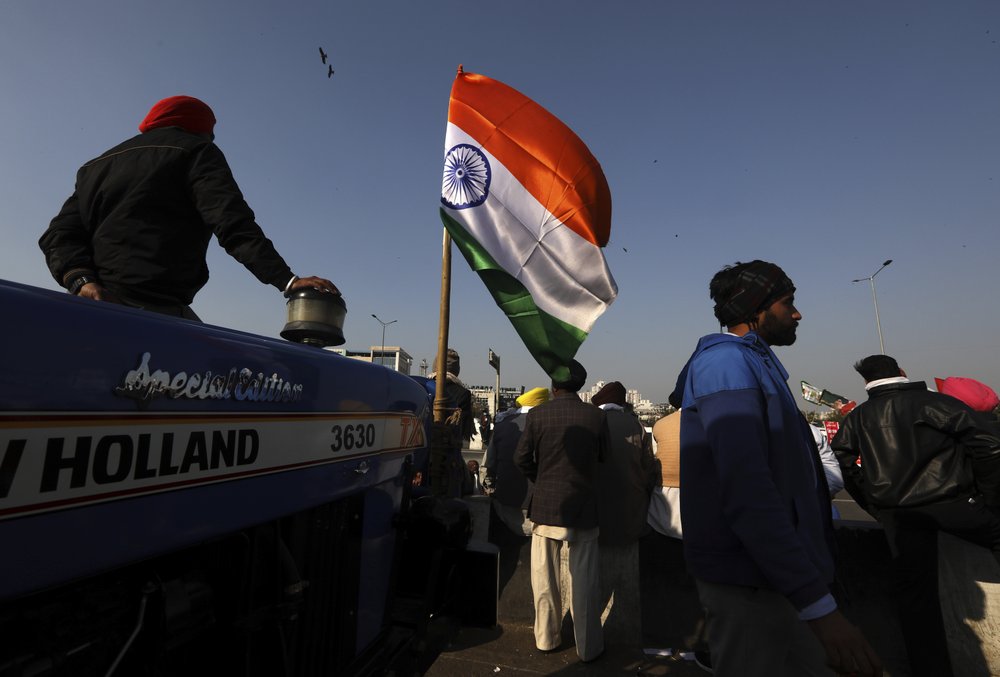 Protesting farmers listen to a speech as they camp on a highway at the Delhi- Uttar Pradesh border