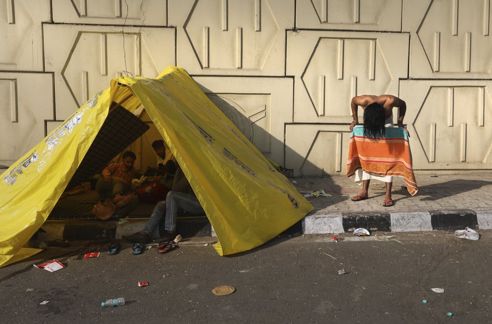 A protesting farmer dries his hair after a bath as he with others camp on a highway at the Delhi- Uttar Pradesh border