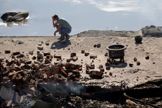 Luke Dexter kneels in front of his father's fire-ravaged beach front property in the aftermath of the Palisades Fire Friday, Jan. 10, 2025 in Malibu, Calif.