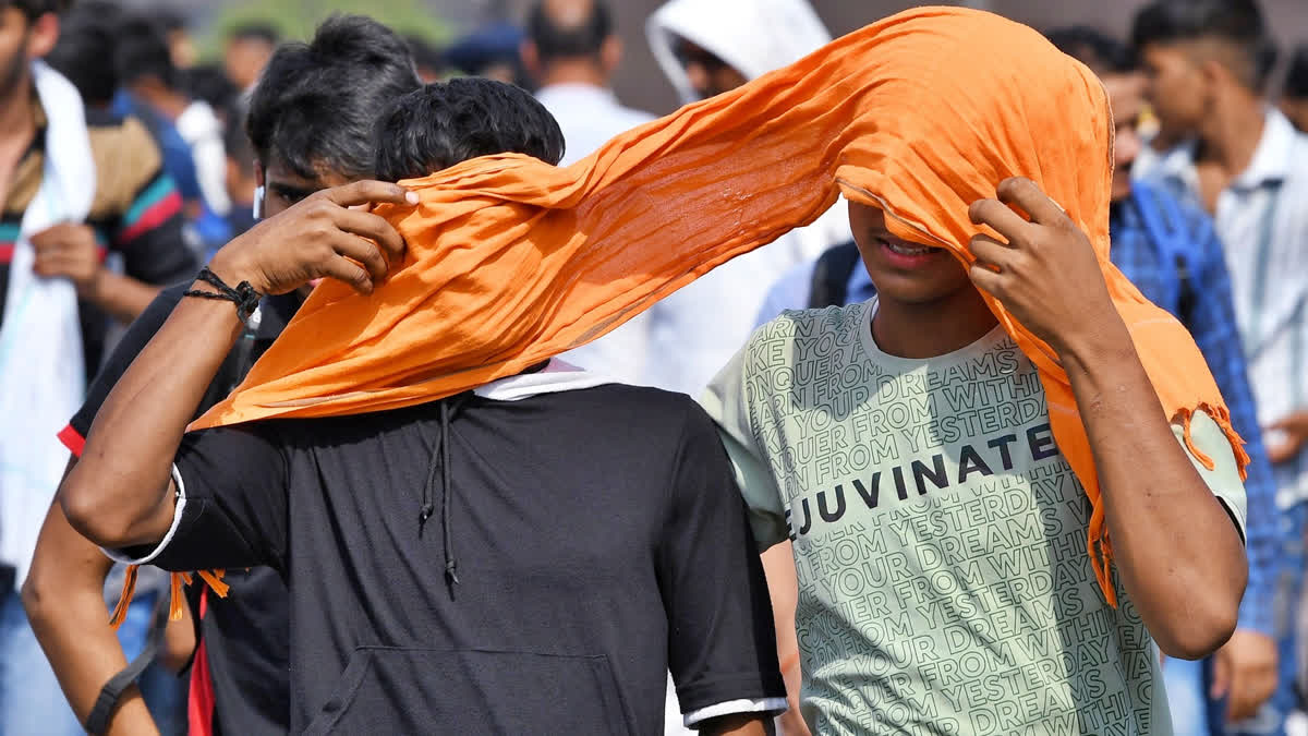 People cover themselves with a scarf to protect from the heat on a hot summer day, in New Delhi.