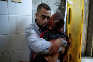 A Palestinian man holds the body of his child killed in the Israeli bombardment of the Gaza Strip, at a hospital morgue in Deir al-Balah, Tuesday, July 9, 2024.