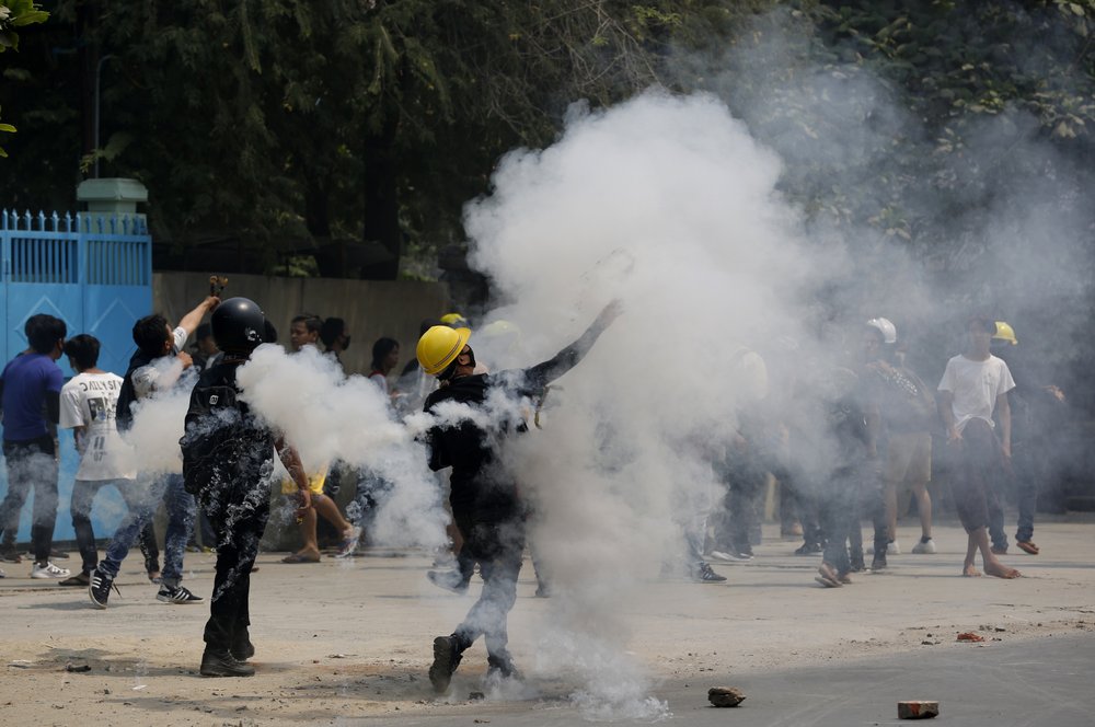 Demonstrators hurl back tear gas canisters towards police during the protest against the military coup in Mandalay