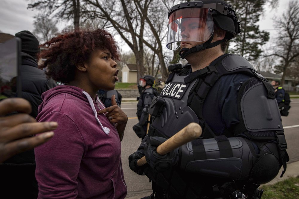 A person confronts a police officer near the site where a family said a man was shot and killed by local law enforcement