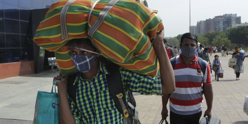 People wearing masks as a precaution against the coronavirus walk to board trains at Lokmanya Tilak Terminus in Mumbai,