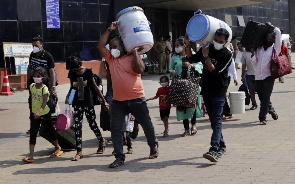 People wearing masks as a precaution against the coronavirus walk to board trains at Lokmanya Tilak Terminus in Mumbai