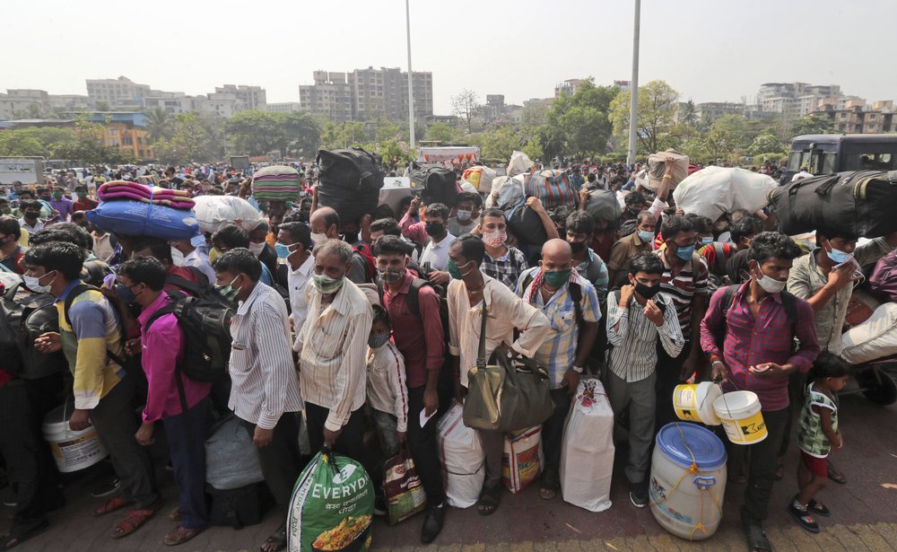 People wearing masks as a precaution against the coronavirus walk to board trains at Lokmanya Tilak Terminus in Mumbai