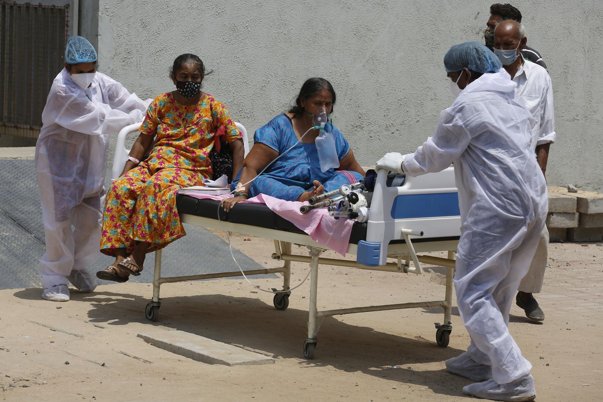 Health worker carry patients to shift them from a dedicated COVID-19 hospital to another hospital to vacate the bed for new patients, at Civil hospital in Ahmedabad