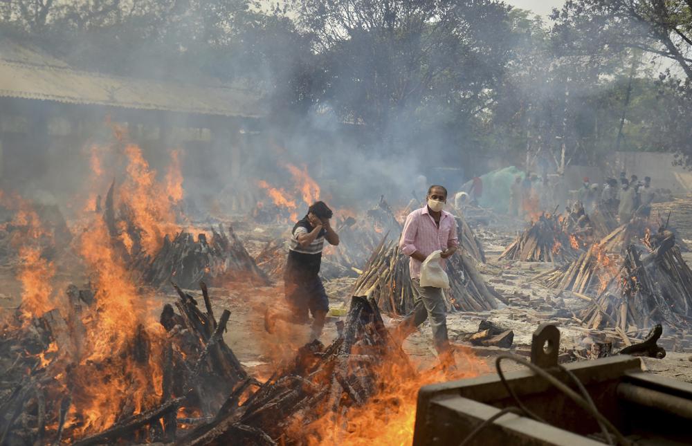 Family members wait to cremate body of a COVID-19 victim at an open crematorium