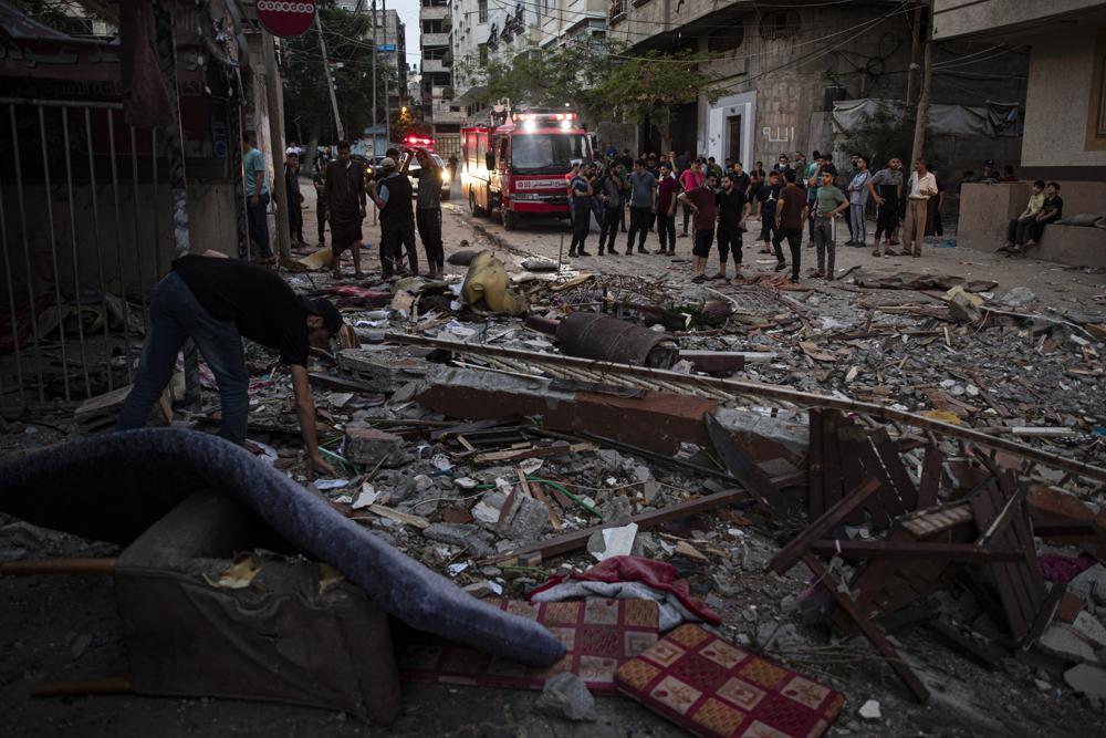 A Palestinian man inspects the rubble of a partially destroyed residential building after it was hit by Israeli missile strikes, at the Shati refugee camp in Gaza City