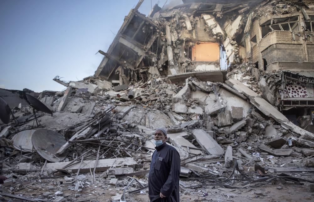 A Palestinian man looks at the destruction of a building hit by Israeli airstrikes in Gaza City