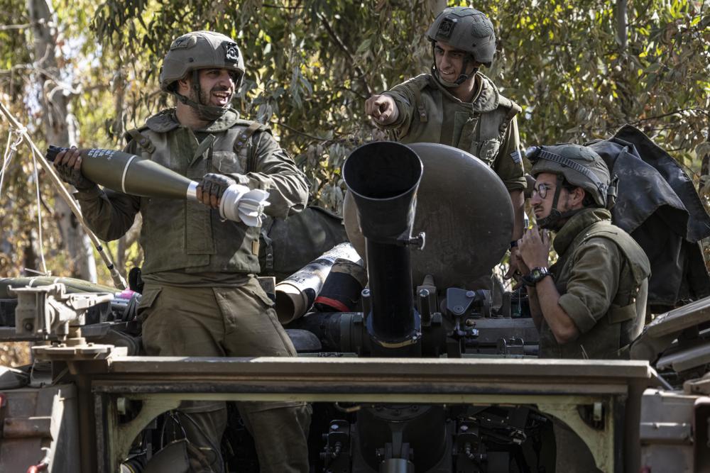 Israeli soldiers load ammunition onto an Armored Personal Carrier (APC) at a staging ground near the Israeli Gaza border