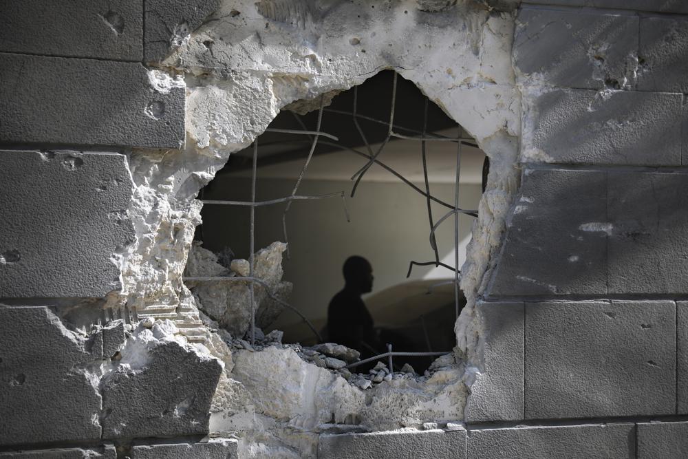 A man is seen trough a hole in a wall of a residential building after it was struck by a rocket fired from the Gaza Strip in Ashkelon, Israel