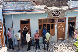 People look at the broken window panes and a damaged portion of a wall of a structure following shelling by Pakistan armed forces, at Akhnoor in Jammu