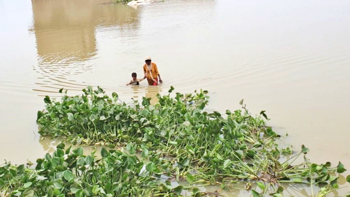 बाढ़ के पानी में मां अपने बच्चे के साथ