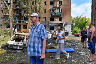 People walk near an apartment building damaged after shelling by the Ukrainian side, in Kursk, Russia, Sunday, Aug. 11, 2024.