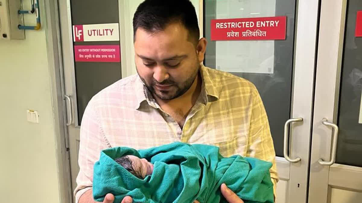 Bihar Deputy Chief Minister Tejashwi Yadav holding his newborn