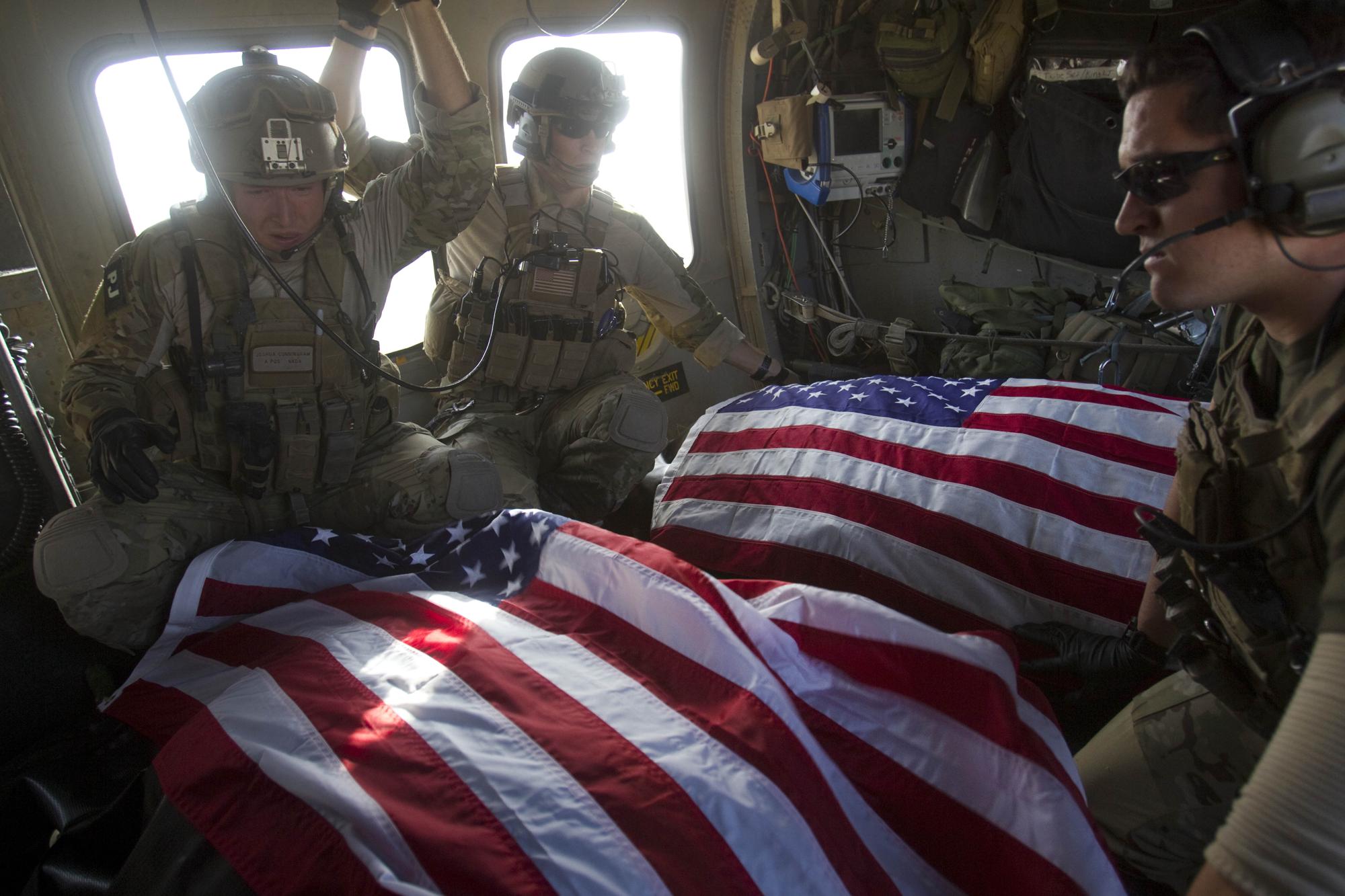 U.S. Air Force pararescue members ride in the back of their medevac helicopter with the American flag draped over bodies of U.S. soldiers who were killed in a roadside bomb attack, Oct. 10, 2010, in Afghanistan's Kandahar province