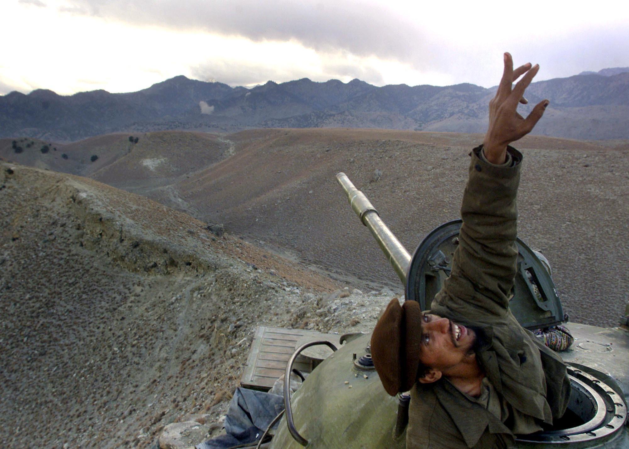 An Afghan anti-Taliban fighter pops up from his tank to spot a U.S. warplane bombing al-Qaida fighters in the White Mountains of Tora Bora in Afghanistan, Dec. 10, 2001.