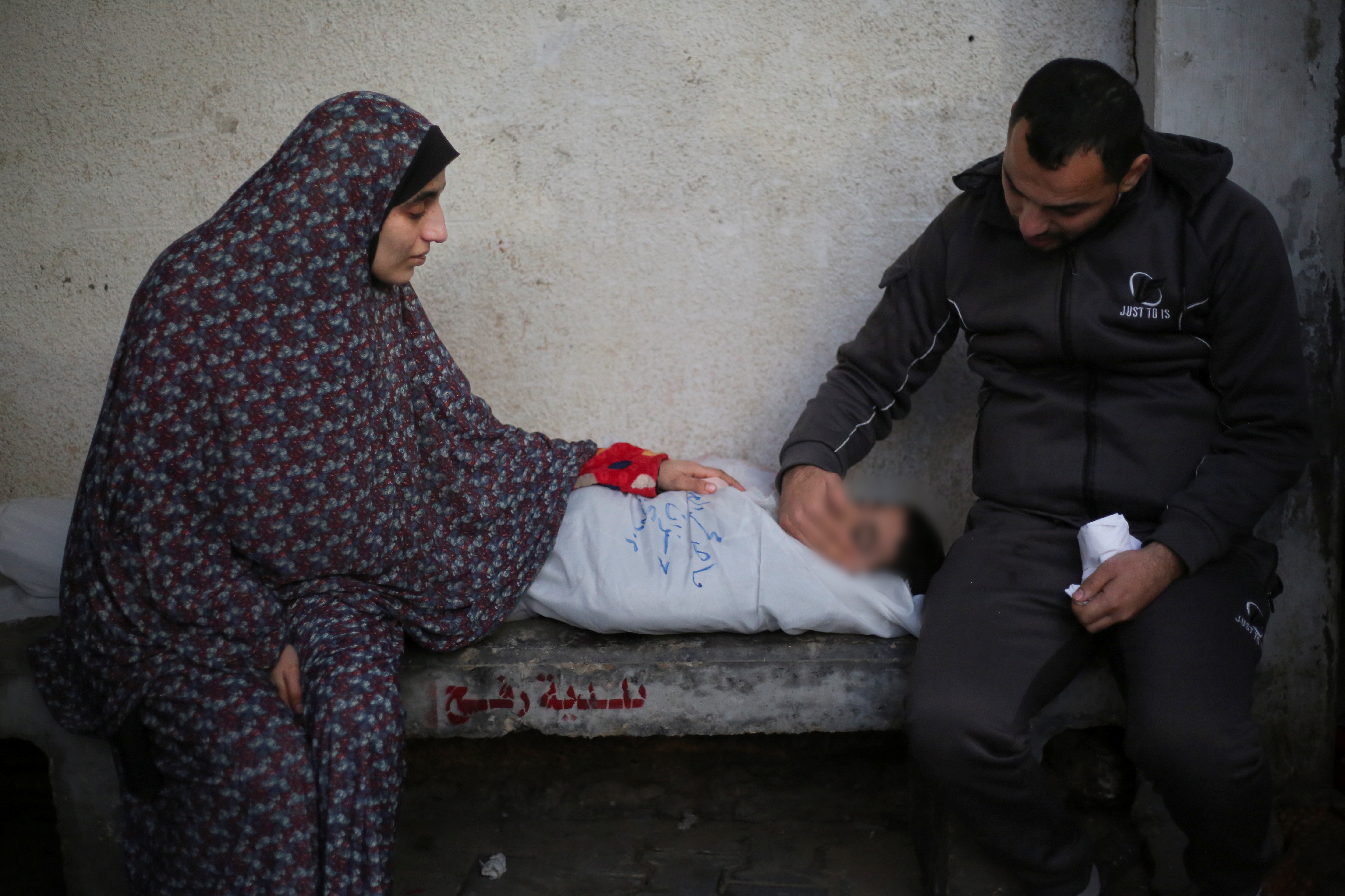فلسطینی غزہ کی پٹی پر اسرائیلی بمباری میں ہلاک ہونے والے رشتہ داروں کو سوموار، 12 فروری، 2024 کو رفح میں ایک ہسپتال کے مردہ خانے میں سوگ منا رہے ہیں۔ (PHOTO: AP)
