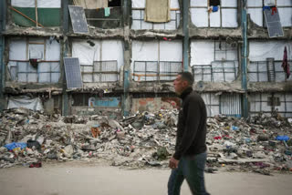 A man walks past a house that remains partly standing, but with sheets serving as makeshift walls and solar panels partly working, in an area largely destroyed by the Israeli army's air and ground offensive in Gaza City, Wednesday, Feb. 5, 2025.