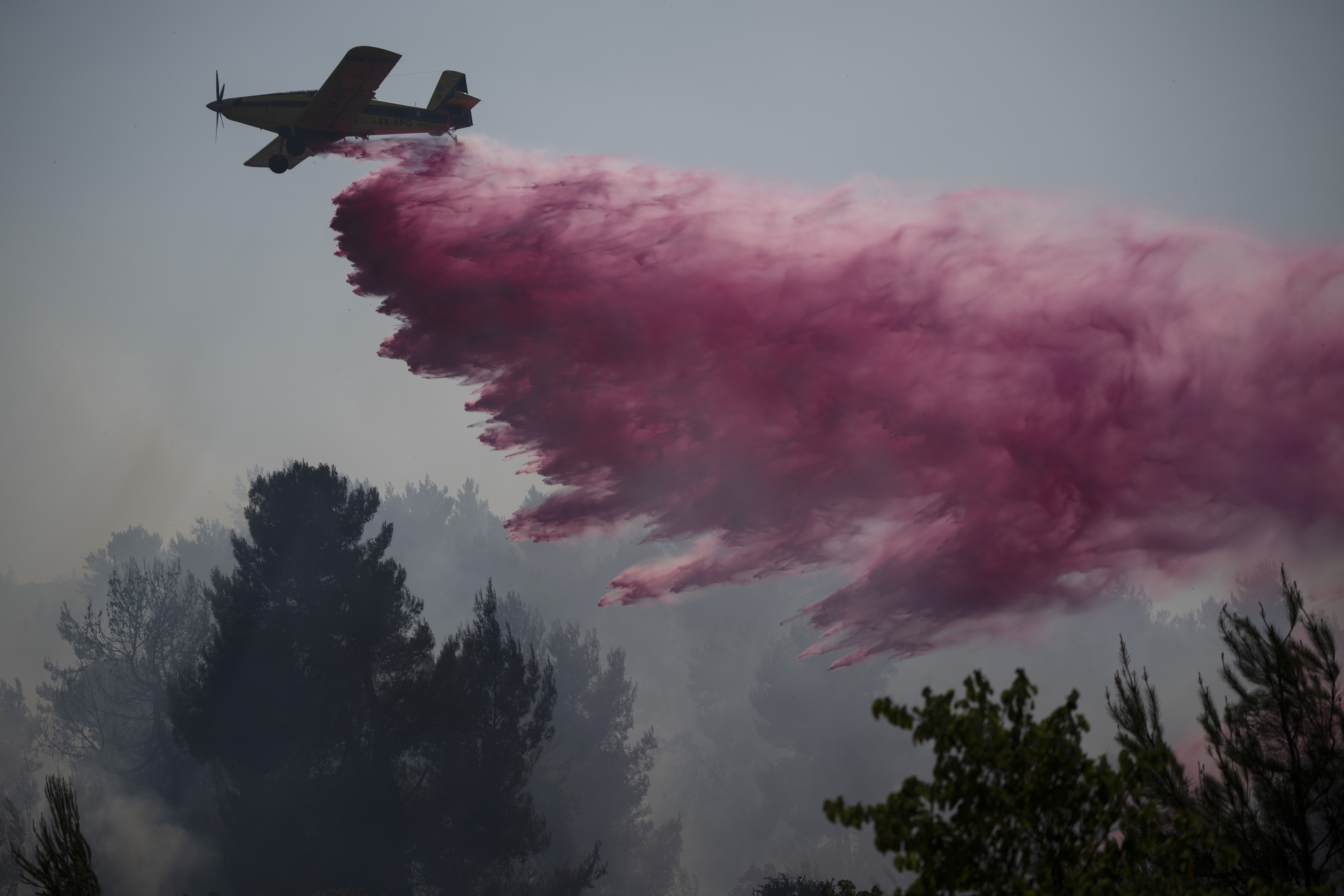 A plane uses a fire retardant to extinguish a fire burning in an area near the border with Lebanon