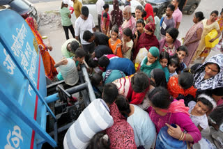 People collect drinking water from a tanker as the national capital faces a water crisis, at New Ashok Nagar area in New Delhi, Wednesday, June 12, 2024.