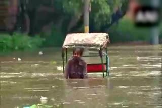 a-rickshaw-puller-pedals-through-chest-deep-water-in-the-flooded-area-near-red-fort-of-delhi