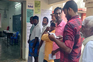 Voters stand in queues to cast their votes for the Vikravandi Assembly by-elections, at a polling station in Viluppurram on Wednesday.