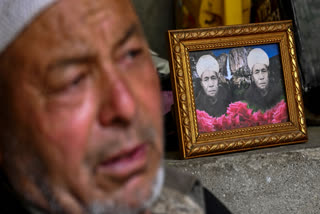 In this photograph taken on July 28, 2024 Ghulam Ahmad, an Indian apricot farmer sits beside a portrait of his father who died in Pakistan, as he speaks during an interview with AFP near Line of Control (LOC) - the border between India and Pakistan, at the Hunderman village in Kargil district.