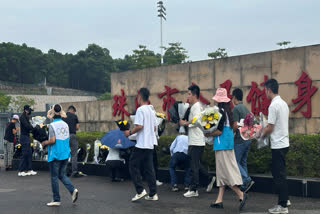 Volunteers relocate flowers laid outside the "Zhuhai People's Fitness Plaza" to a barrier leading into the area where a man rammed his car into people exercising at the sports center, in Zhuhai in southern China's Guangdong province on Wednesday, Nov. 13, 2024.