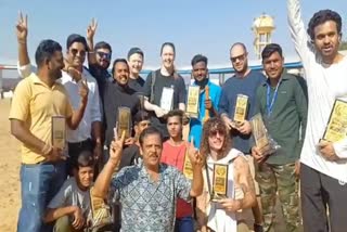 Foreign tourists and locals pose for a picture after a cricket match at Pushkar Mela at Ajmer, Rajasthan