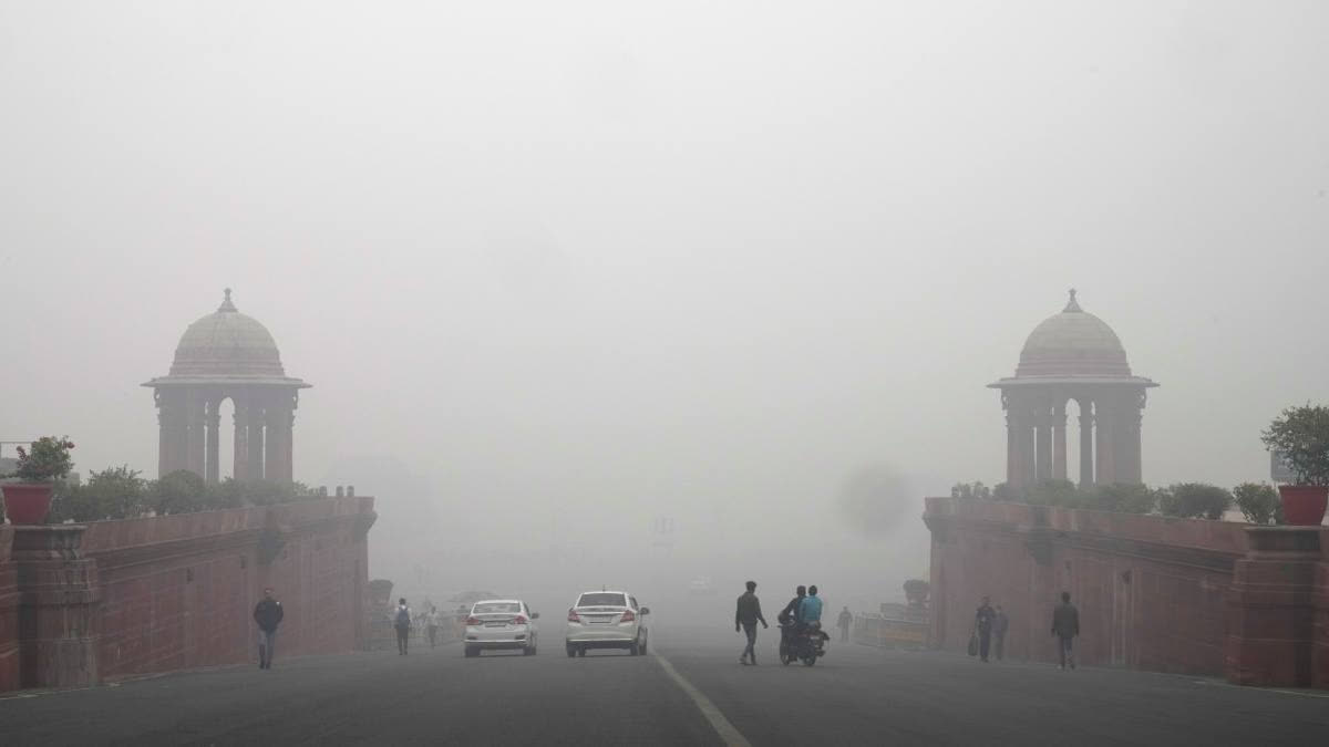 Commuters walk amidst a thick layer of smog in New Delhi