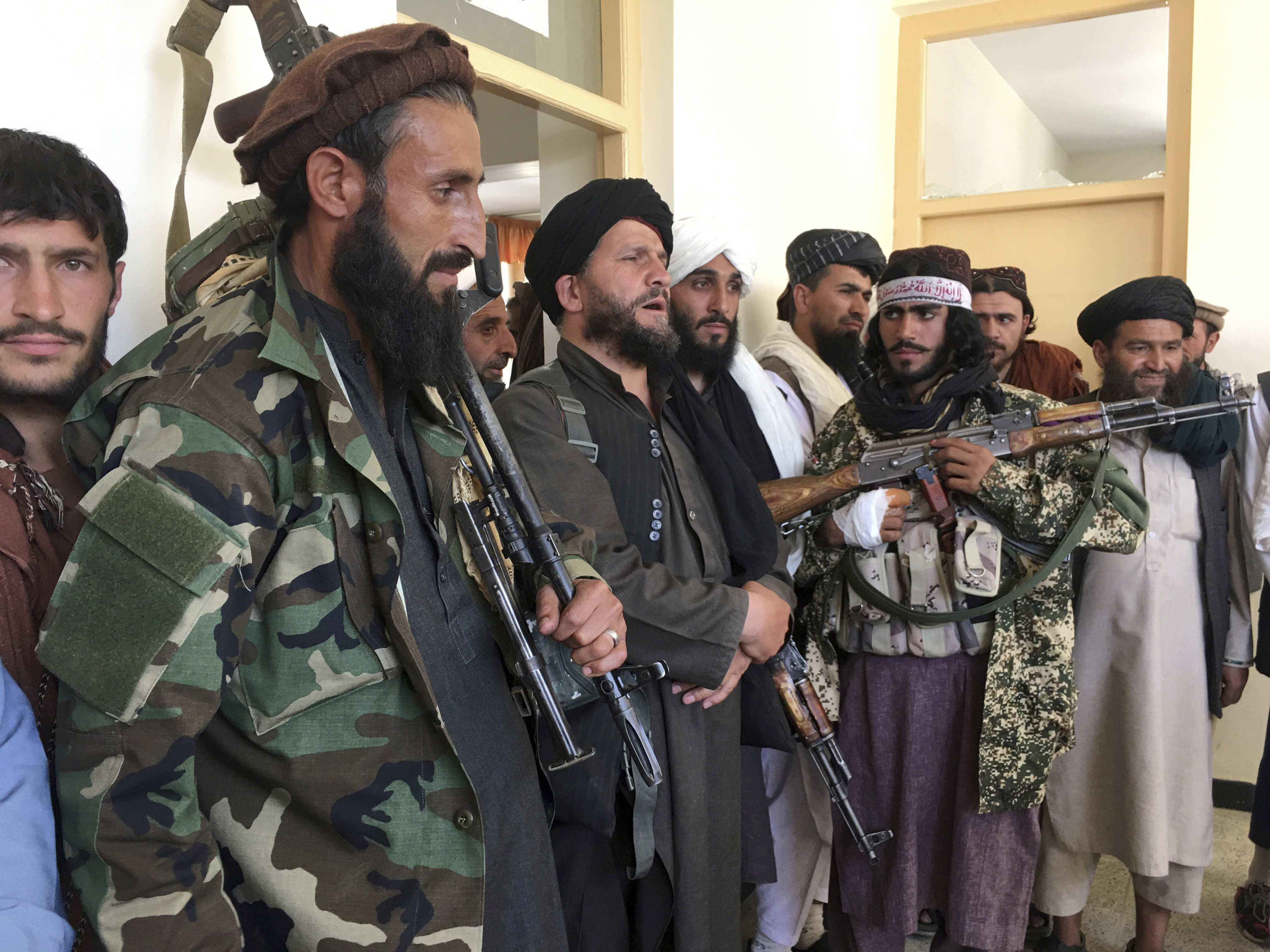 Taliban soldiers stand guard over surrendered Afghan Militiamen