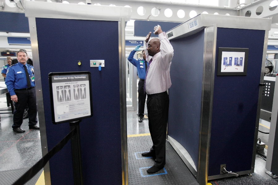 In this March 15, 2010 file photo, a volunteer passes through the first full body scanner installed at O'Hare International Airport in Chicago. The technology produces a cartoon-like outline rather than naked images of passengers by using X-rays.