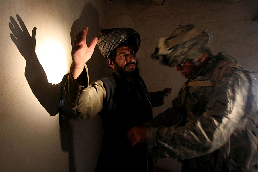 In this Monday, April 2, 2007 file photo, a U.S. soldier of B company, 4th Infantry Regiment frisks an afghan man in his house during a search operation in Sinan village in Zabul province, southeastern Afghanistan.