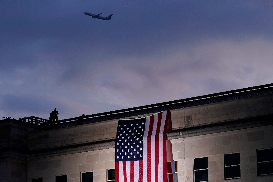 In this Friday, Sept. 11, 2020 file photo, a plane takes off from Washington Reagan National Airport as a large U.S. flag is unfurled at the Pentagon ahead of ceremonies at the National 9/11 Pentagon Memorial to honor the 184 people killed in the 2001 terrorist attack on the Pentagon, in Washington, Friday, Sept. 11, 2020.