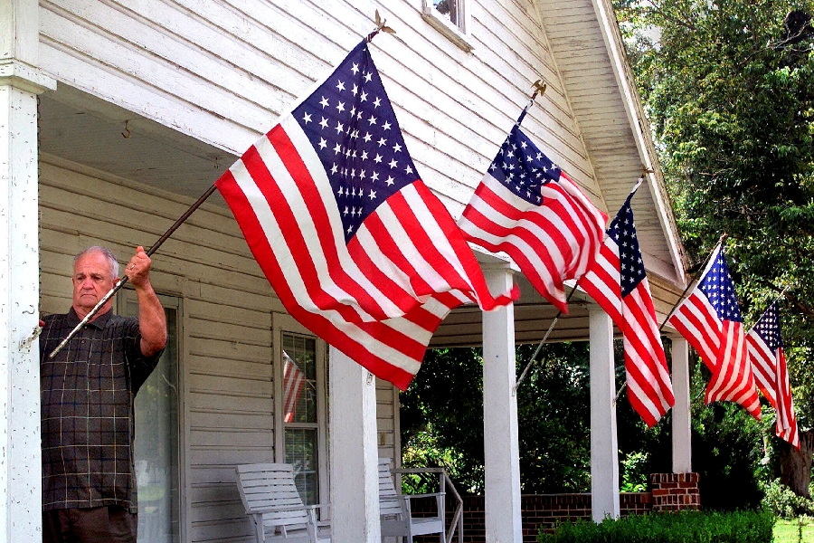 In this Thursday, Sept. 13, 2001 file photo, Liberty County resident Rev. M. Timonthy Elder, Sr., retired, repositions one of his wind-blown U.S. flags in Bristol, Fla. Rev. Elder displayed the flags as a show of his family's support for America following terrorist attacks in New York City and Washington two days earlier.