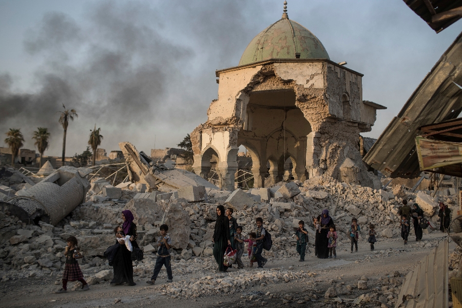 In this Tuesday, July 4, 2017 file photo, fleeing Iraqi civilians walk past the heavily damaged al-Nuri mosque as Iraqi forces continue their advance against Islamic State militants in the Old City of Mosul, Iraq. As Iraqi forces continued to advance on the last few hundred square kilometers of Mosul held by the Islamic State group, the country's Prime Minister said Tuesday the gains show Iraqis reject terrorism.