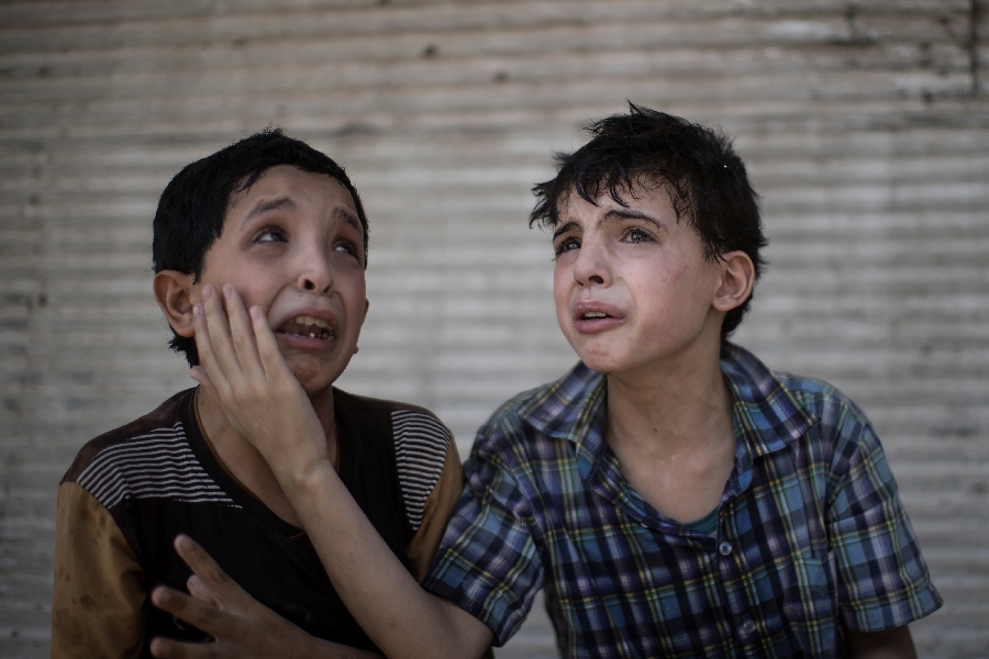 In this Saturday, June 24, 2017 file photo, Zeid Ali, 12, left, and Hodayfa Ali, 11, comfort each other after their house was hit and collapsed during fighting between Iraqi forces and Islamic State militants in Mosul, Iraq. The Ali cousins said some of their family members are still under the rubble.