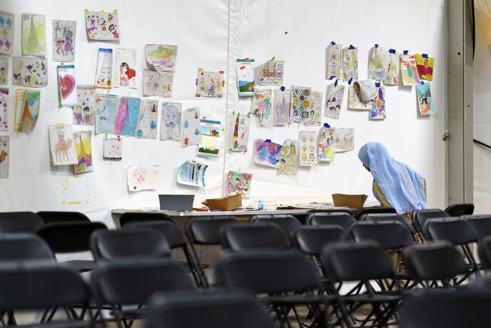 A child holds up a piece of artwork while drawing in a tent at Fort Bliss' Doña Ana Village, in New Mexico, where Afghan refugees are being housed,