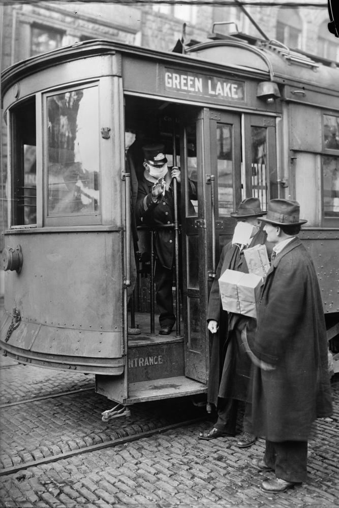 In this 1918-1919 photo made available by the Library of Congress, a conductor checks to see if potential passengers are wearing masks in Seattle, Wash. During the influenza epidemic, masks were required for all passengers.