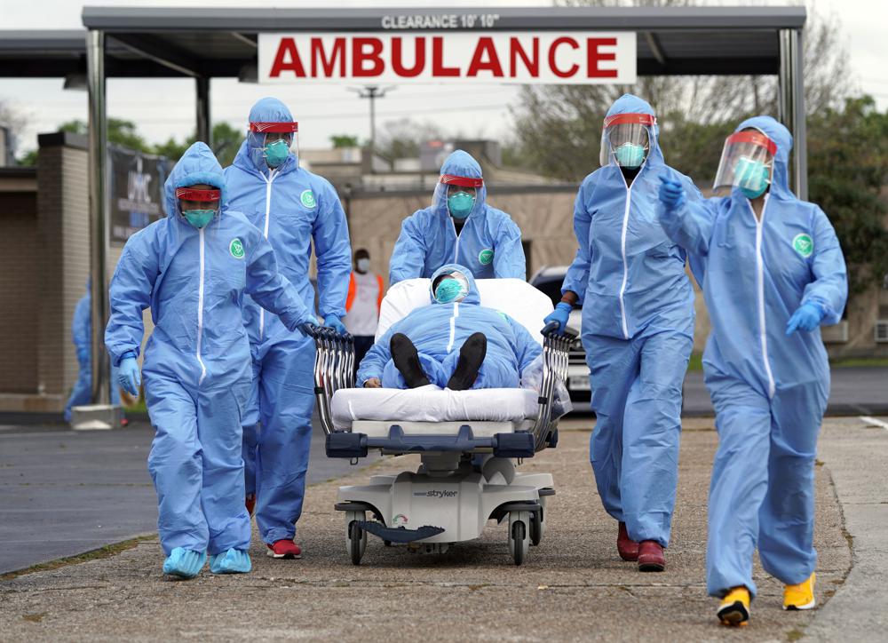 A patient is taken on a stretcher into the United Memorial Medical Center after going through testing for COVID-19 in Houston. People were lined up in their cars in a line that stretched over two miles to be tested in the drive-thru testing for coronavirus.